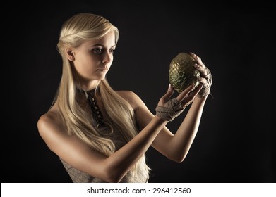 attractive woman in dress holding a dragon egg in hands