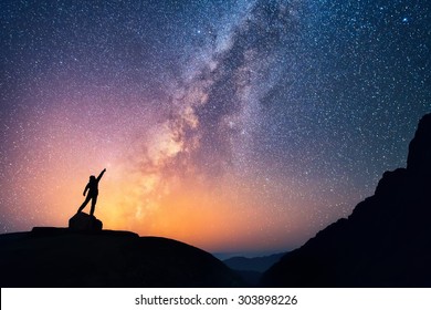 Cazador de estrellas. Una persona está de pie junto a la Vía Láctea apuntando a una estrella brillante.