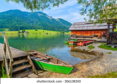 Barcos de pesca y casa de madera en la orilla del lago Weissensee en el paisaje de verano de la tierra de Carintia, Austria