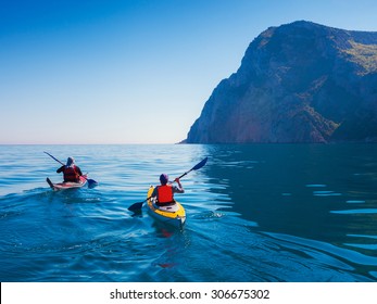 Kayaks. Pareja kanoeing en el mar cerca de la isla con montañas. Gente haciendo kayak en el océano.