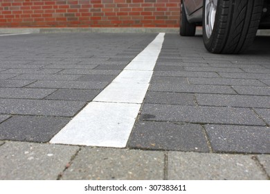ホワイトカラーのタイルを使用した駐車スペースの目印。背景に駐車中の車。