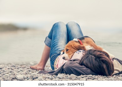 Kleine beagle pup liggend op de borst van zijn baasje aan de zeezijde