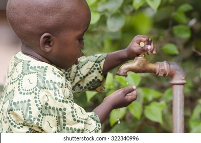 Young African school boy holding hands under a tap. Water scarcity problems concern the inadequate access to safe drinking water. 1 billion people in the developing world don't have access to it.