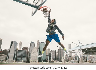 cầu thủ bóng rổ biểu diễn slum dunk trên sân đường phố. nền với các tòa nhà manhattan