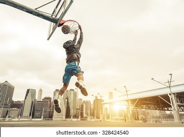 Jugador callejero de baloncesto haciendo una volcada trasera. Edificios de Nueva York y Manhattan en el fondo
