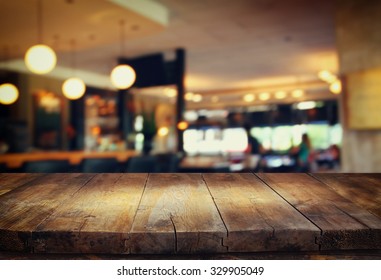 imagen de una mesa de madera frente a un fondo borroso abstracto de las luces del restaurante