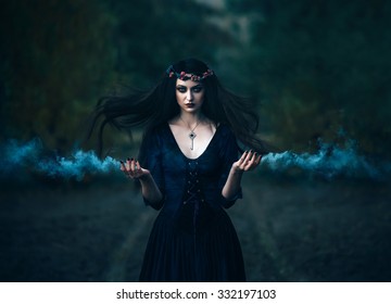 Fantasy horror woman witch medieval old purple outfit clothes dress. key on neck. Gothic magic portrait. Evil  makeup face Art scary Magician spell smoke hands. Hair flutter fly wind night forest road