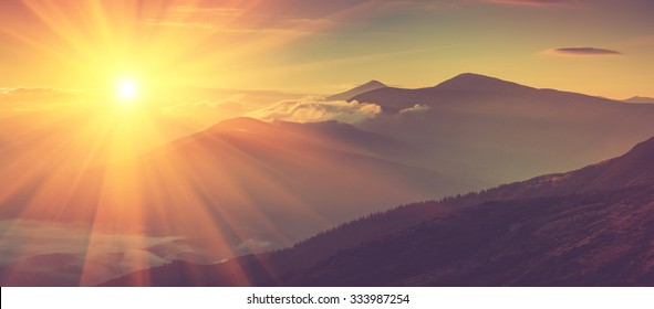Panoramisch uitzicht op bergen, herfstlandschap met mistige heuvels bij zonsopgang. Gefilterde afbeelding: kruis verwerkt vintage effect.