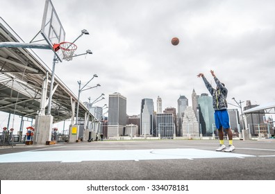 Cầu thủ bóng rổ tập bắn trên sân. Nền New York và các tòa nhà Manhattan