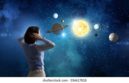 Wanita muda menutup telinganya dengan tangan dan melihat planet angkasa lepas