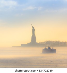 El ferry de Staten Island pasa junto a la Estatua de la Libertad en un brumoso atardecer. Manhattan, Ciudad de Nueva York, Estados Unidos de América. Composición cuadrada.