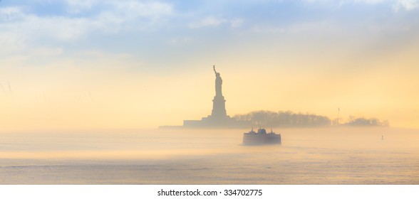 El ferry de Staten Island pasa junto a la Estatua de la Libertad en un brumoso atardecer. Manhattan, Ciudad de Nueva York, Estados Unidos de América. Composición panorámica. Copie el espacio.