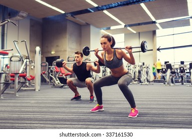 sport, bodybuilding, levensstijl en mensenconcept - jonge man en vrouw met barbell die spieren buigen en schouderpers squat maken in de sportschool