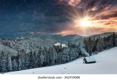 Noche colorida de invierno en las montañas al atardecer. Cielo nublado dramático y nevando. Vista de la antigua granja y cerca turística.