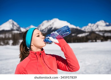 Mujer joven trotando afuera en las soleadas montañas de invierno