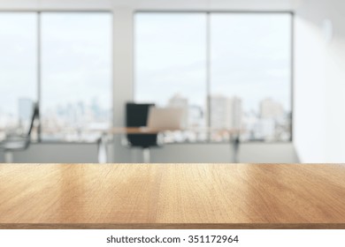 Masă de lemn într-un birou însorit cu ferestre mari