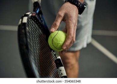 Primer plano de la mano masculina que sostiene la pelota de tenis y la raqueta. Set inicial de tenista profesional.