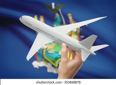 Airplane in hand with local US state flag on background - New York