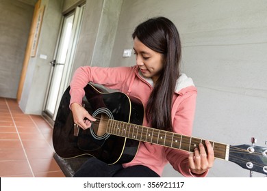 Jonge vrouw speelt thuis met gitaar