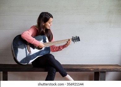 家でギターを弾く女性