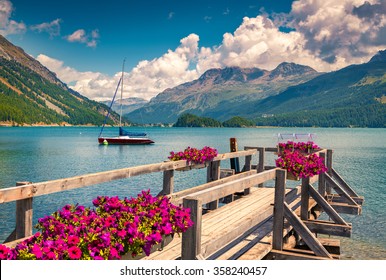ヨットと花が咲くシルサー湖の夏の日当たりの良いシーン。スイスアルプス。セーグル、スイス、ヨーロッパ。レトロなスタイルのフィルター。