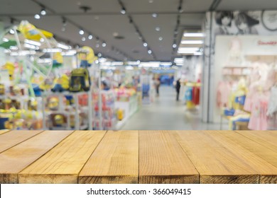 Bahagian atas meja kayu kosong dengan latar belakang kabur gedung mainan, Pusat beli-belah bokeh semula jadi Kedai Mainan, warna vintaj.- boleh digunakan untuk montaj atau memaparkan produk anda