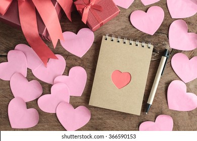 Bentuk hati merah dengan bunga dan nota di atas meja kayu lama, konsep Valentine
