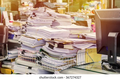 Pile of documents on desk stack up high waiting to be managed.