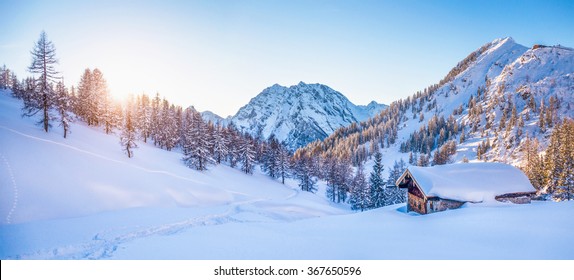 Vista panorámica del hermoso paisaje montañoso del país de las maravillas del invierno con una cabaña de montaña tradicional al fondo en los Alpes a la luz dorada de la tarde al atardecer