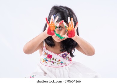 Cute little Indian girl showing her colourful hands/palm printing or playing holi festival with colours, isolated over white background