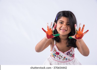 Cute little Indian girl showing her colourful hands/palm printing or playing holi festival with colours, isolated over white background
