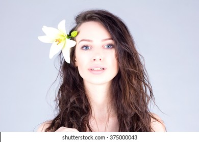 Woman with curly hair and big blue eyes. Woman with a flower in her hair.