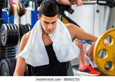 Sterke man kijkt naar beneden en werkt met halters zijn lichaam in de sportschool. Portret van knappe man.