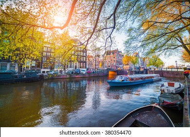 Spring scene in Amsterdam city. Tours by boat on the famous Dutch canals. Colorful evening landscape in Netherlands, Europe.