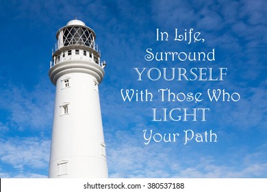 Leuchtturm mit einem inspirierenden Motivationszitat von In Life Surround Yourself mit denen, die Ihren Weg vor einem teilweise bewölkten Himmel Hintergrund beleuchten