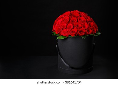 黒の背景スタジオ、スタジオ写真、春が来る、国際女性の日、ロゴのためのスペースを持つ黒のギフト ボックスにロマンチックな豪華な赤いバラ