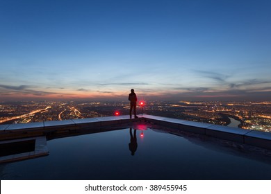 Mann am Dachrand eines Wolkenkratzers bei Nacht