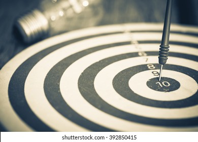Smart goal setting, dart hit the center of dartboard with light bulb on background