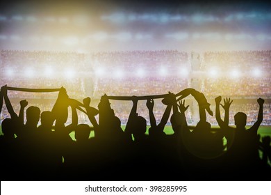 Silhouettes of soccer or rugby supporters in the stadium during match