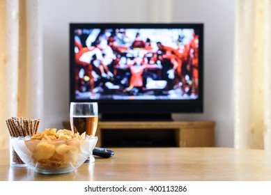 Televisyen, menonton TV (perlumbaan formula satu) dengan makanan ringan dan alkohol di atas meja - stok foto