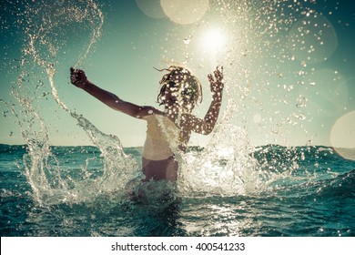 Glückliches Kind, das im Meer spielt. Kind hat Spaß im Freien. Sommerferien und gesundes Lifestyle-Konzept. Getöntes Bild