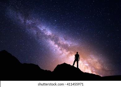 天の川のある風景。星と岩の上の幸せな男のシルエットの夜空。美しい宇宙。宇宙背景