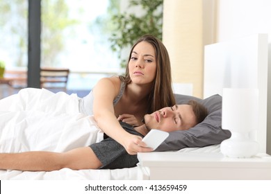 Jaloerse vrouw bespioneert de scherpte van haar partner terwijl hij thuis in een bed slaapt
