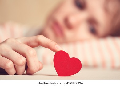 Gadis sedih dan kesal menyentuh simbol hati dengan jari dan melihatnya. Wanita berpikir tentang cinta tak berbalas dan kesulitan hubungan. Fokus ada di hati. Konsep cinta dan hubungan