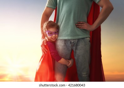 幸せな愛情のある家族。父と娘の子供の女の子が野外で遊んでいます。スーパーヒーローの衣装を着たパパと彼の子供の女の子。父の日のコンセプト。