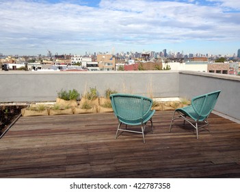 Rooftop in Brooklyn met twee groene rieten stoelen op hardhouten vloeren