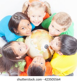 Groep internationale gelukkige kinderen die de wereldbol vasthouden en omhoog kijken naar de camera. Schoolkinderen leren aardrijkskunde. Multi-etnische mensen. Wereld. Ecologie. Zuivere aarde. Internationale Kinderdag