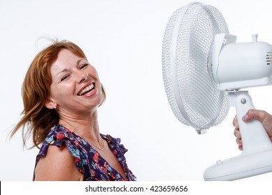 Mulher no estúdio sorri enquanto o ar de um ventilador portátil sopra em seu cabelo
