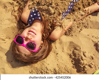 Concetto di divertimento e gioia. Piccola, adorabile, splendida ragazza dai capelli lunghi che gioca con la sabbia del mare. Bambina attiva e giocosa in spiaggia durante le vacanze estive.