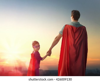 幸せな愛情のある家族。父と娘の子供の女の子が野外で遊んでいます。スーパーヒーローの衣装を着たパパと彼の子供の女の子。父の日のコンセプト。